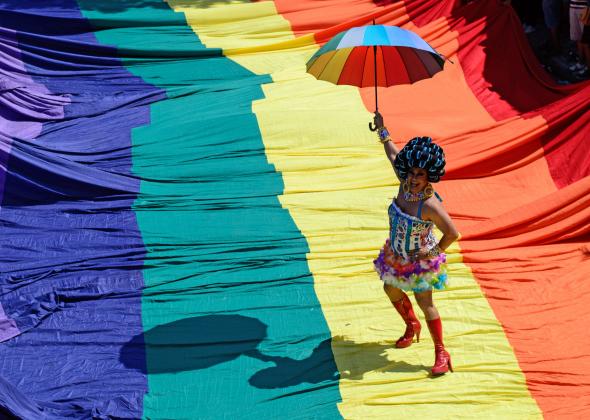 459080120-reveller-poses-on-a-giant-rainbow-flag-during-the.jpg.CROP.promo-mediumlarge